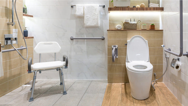 Accessible bathroom with white fixtures: a toilet with grab bars, a shower area with chair, wooden shelves holding towels. Image