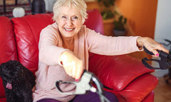 Woman sitting on a red couch with a black dog, holding a rollator.