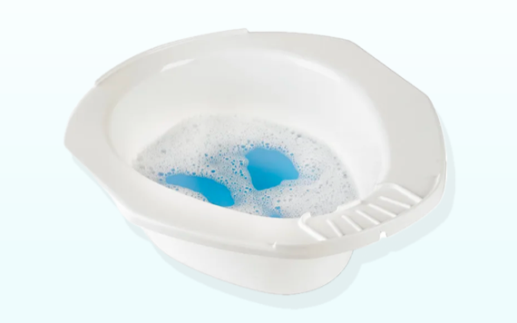 A white plastic basin filled with blue water and white soap bubbles. The basin has a small ledge with ridges designed for scrubbing.