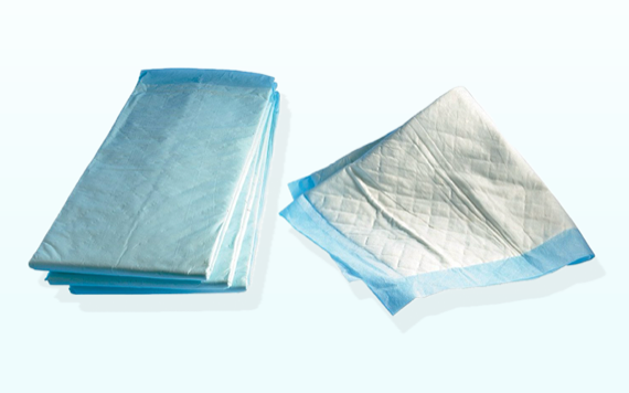 A stack of blue incontinence pads is on the left, and one unfolded pad is on the right. The pads have a quilted pattern on their surface and a blue border, set against a light background. Image