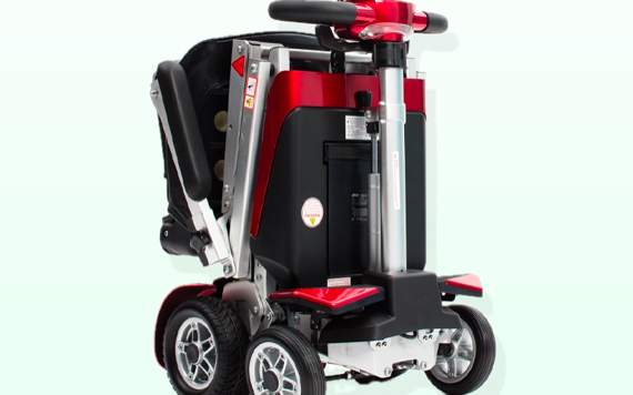 A compact, foldable electric mobility scooter in black and red with four wheels, a cushioned seat, handlebars, and a sturdy frame.