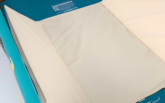 A teal machine with visible mechanics, neatly stacks and folds cream-colored paper or envelopes, showcasing its industrial design.