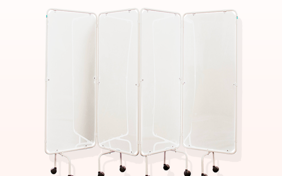 Two nurses conversing in a hospital hallway with blue walls, large windows, and medical carts nearby.