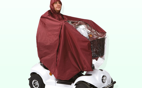 A person in a maroon rain cover with a hood sits on a white mobility scooter. Reflective front, light green background.