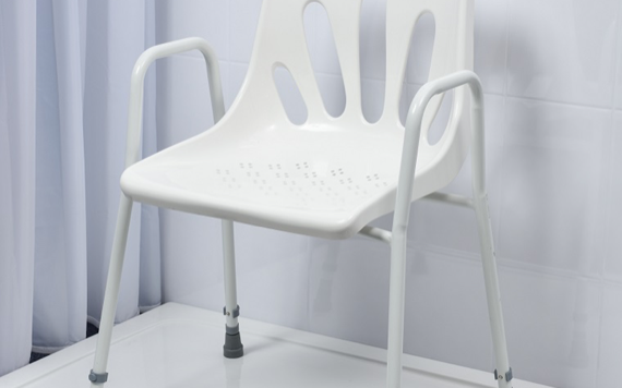 White plastic chair with armrests, vented backrest, and metal frame on a glossy white floor, near light-colored curtains.