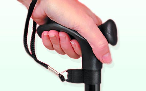 A hand grips a black walking cane with a wrist strap. The background fades softly from light green to white.