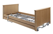 Sidhil Bradshaw Low Bed in light oak with metal slats, side rails, and wheels, no mattress, angled view.