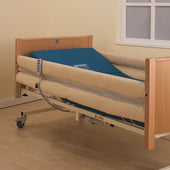 Sidhil bed with side rail mesh pads and blue mattress, light walls and flooring, room setting, angled view.