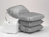 Inflatable grey bathing cushion with attached white air pump, reclined position, front view.