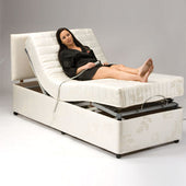 Woman lying on Restwell Reflex Foam Mattress in adjustable bed, holding remote, head and legs raised, in use view.