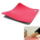 Red flexible RoMedic Antislip Mat with corner hole placed under a desk as a high-friction footrest, in use view.