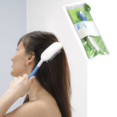 Etac Hair Brush 290 mm used by a woman with dark hair, with green packaging shown beside, in use and packaging view.