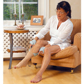 Etac Socking Aid for Support Stockings helping an older woman put on compression stockings, seated by a window, in use view.