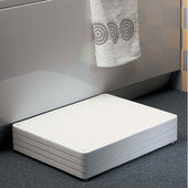 White height adjustable bath step on dark floor beside bathtub with a towel above, side view.