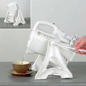 Homecraft Universal Kettle Tipper tilting a white cordless kettle to pour hot water into a brown cup, one-handed use, side view.