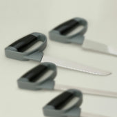 Homecraft Comfort Grip Carving Knife with slip resistant handle, three similar knives blurred in background, front view.