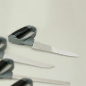 Homecraft Comfort Grip Chefs Knife with grey and black soft-touch handle, two more knives partly shown on a light background, top view.