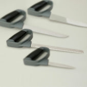 Set of four bread knives with soft-touch handles on a white surface, one knife in clear focus, top view.
