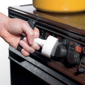 Hand turning a stove control knob with the Homecraft Contour Knob Turner, in use close-up.