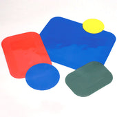 Four plastic shapes on a green Dycem non-slip mat, white background, top view.