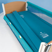 Sidhil Solite Mattress Infill (Loose) with teal bumpers, mesh rail, and wood headboard in a blue room, front view.