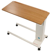 Overbed table with woodgrain top, white metal frame and four castor wheels, side view.