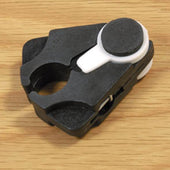 Able2 cane or crutch holder, black and white plastic clip-on design, shown on a wooden surface, close-up.