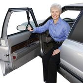Older woman holding Able2 Car Caddie support strap attached to car door, using it to help exit the vehicle, side view.
