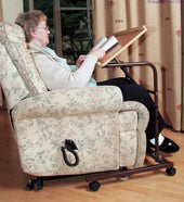 Able2 Economy Over Chair Table with manual height adjustment in use by an older woman indoors, side view.