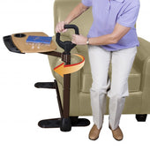 Stander Assist-A-Tray Over Chair Table with grab handle next to a chair, shown in use, side view.