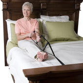 Older woman holding Stander Bed Caddie to sit up in bed, smiling, product in use, front view.