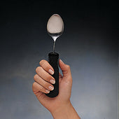 Good Grips Teaspoon with large black easy-grip handle held in hand, gradient background, close-up.
