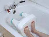 Feet on Gordon Ellis Ashby Bath Shortener in a tub, faucet in background, shows non-slip surface, in use view.