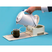 White kettle on Gordon Ellis Stability Base tipping hot water into brown mug, in use close-up.