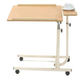 Brown overbed table with split level, angle adjustable top, wheels and side tray, shown holding a cup and saucer, angled view.