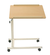 Cream overbed table with height-adjustable top, white frame and castor wheels, bedside use, angled side view.