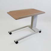 Adjustable overbed table with a wooden top and metal base on wheels, suitable for use by a bed or chair, side view.