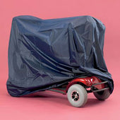Mobility scooter partially covered by a dark blue Homecraft storage cover, pink background, side view.