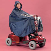 Person wearing a blue scooter cape using a red mobility scooter, pink background, side view.