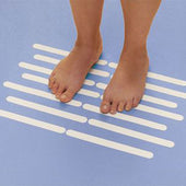 White Homecraft Bath Safety Strips in parallel lines on a blue floor with bare feet, in use top view.