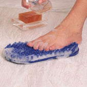 Foot being cleaned on Soapy Soles pad with foam, bar of soap in clear dish beside it, in use close-up.