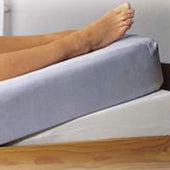 Homecraft Mattress Tilter under legs in bed for ankle swelling and vein support, in use side view.
