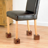 Wooden chair on Homecraft Wooden Chair Raisers placed on light wood floor beside a wooden cabinet, side view.