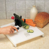 Homecraft Food Preparation System in use for one-handed cucumber slicing, with carrots, bread, and milk visible on the counter, side view.