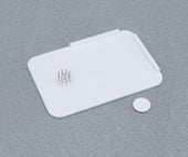 Homecraft plastic spreadboard with metal spikes and round disc on a grey textured surface, top view.