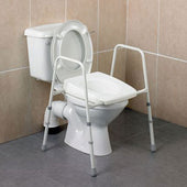 White toilet with adjustable Homecraft Stirling toilet frame and non-slip feet on beige and grey tiled floor, front view.