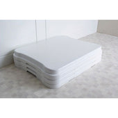 Stack of three NRS Adjustable Bath Steps on a light tiled floor beside a wall, side view.