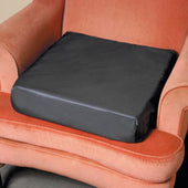 Black NRS Easy Rise Cushion placed on an orange armchair, designed to support getting up more easily, front view.