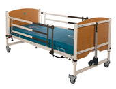 Hospital bed with wooden head and foot boards, Sidhil Grange Side Rails, blue mattress and castor wheels, side view.