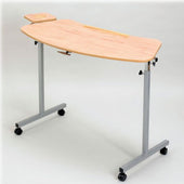 Height-adjustable over armchair table with wheels, laminated teak top, side platform and metal legs, front angle view.